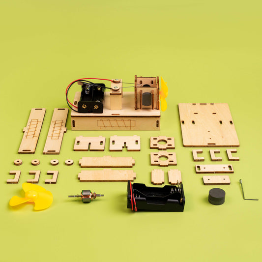 Electric motor DIY kit parts laid out on board: wooden frame, coils, wires, and yellow propellers