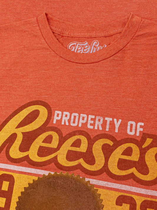 Orange heather T-shirt neckline with Teeluv logo and Property of Reese's text