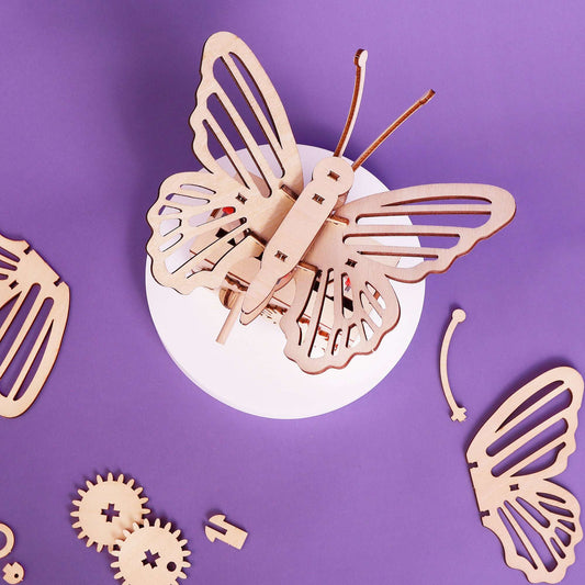 Butterfly DIY kit model with raised wings and connector rods, gears visible on base