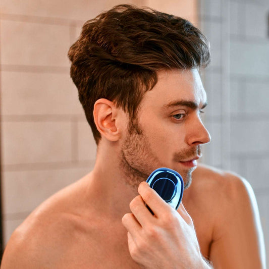 Blue electric shaver held to a man’s cheek for close shaving
