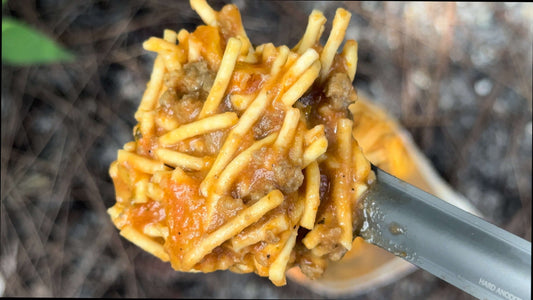 Saucy spaghetti with meat sauce, freeze-dried noodles on spoon.