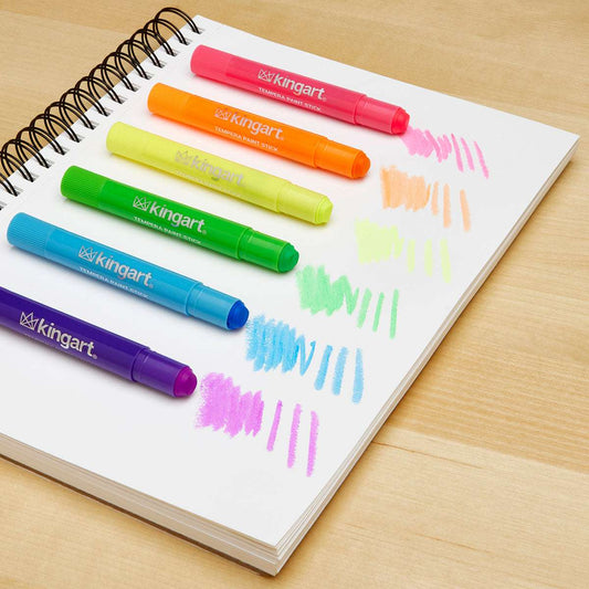 Set of tempera paint thin sticks with colored marks on a sketchbook page.
