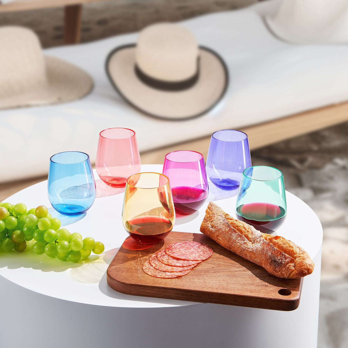 Assorted color stemless acrylic wine glasses on a table with bread and grapes