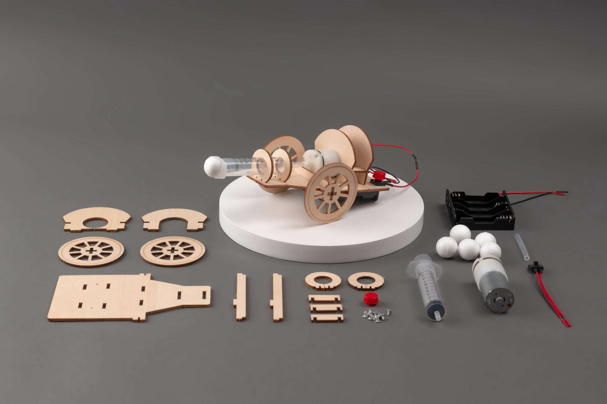 Cannon DIY STEM kit parts laid out: wooden pieces, launcher parts, and red wires
