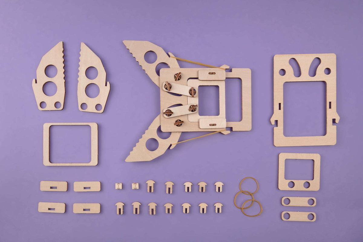 Flat lay of wooden mechanical claw kit pieces, screws, and elastic cord