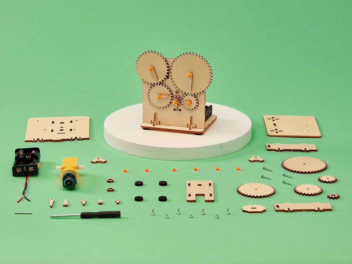 STEM gear train DIY kit with wooden frame, orange pins, motor, and loose parts