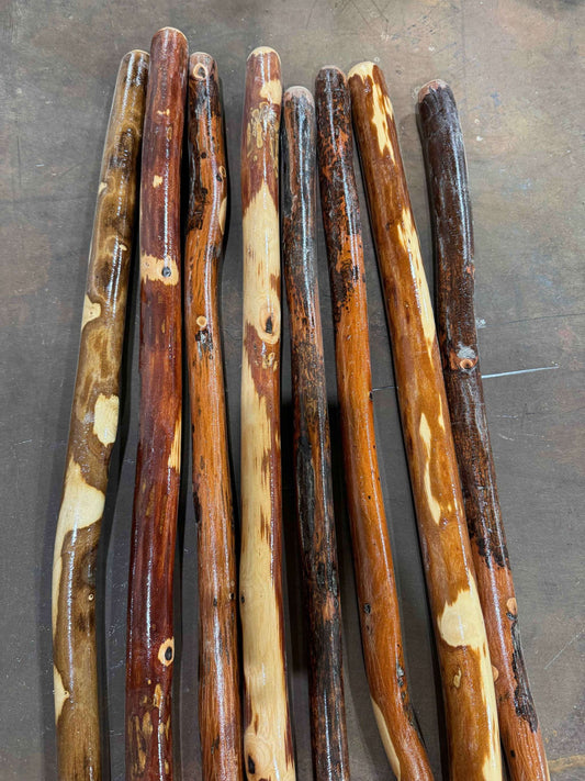 Assorted wooden hiking sticks with varied grains, dark and pale wood tones
