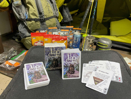Waterproof survival playing cards with guide text and a small deck on a tray