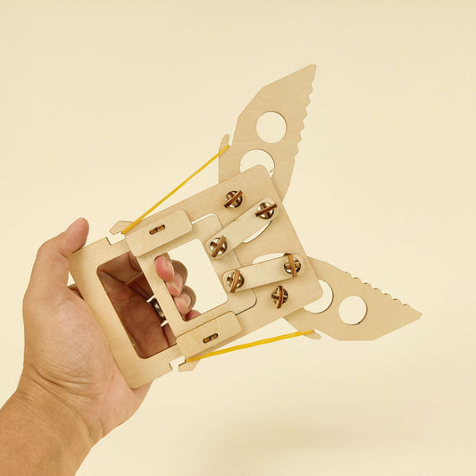 Wooden mechanical claw kit held in hand, showing latch and string