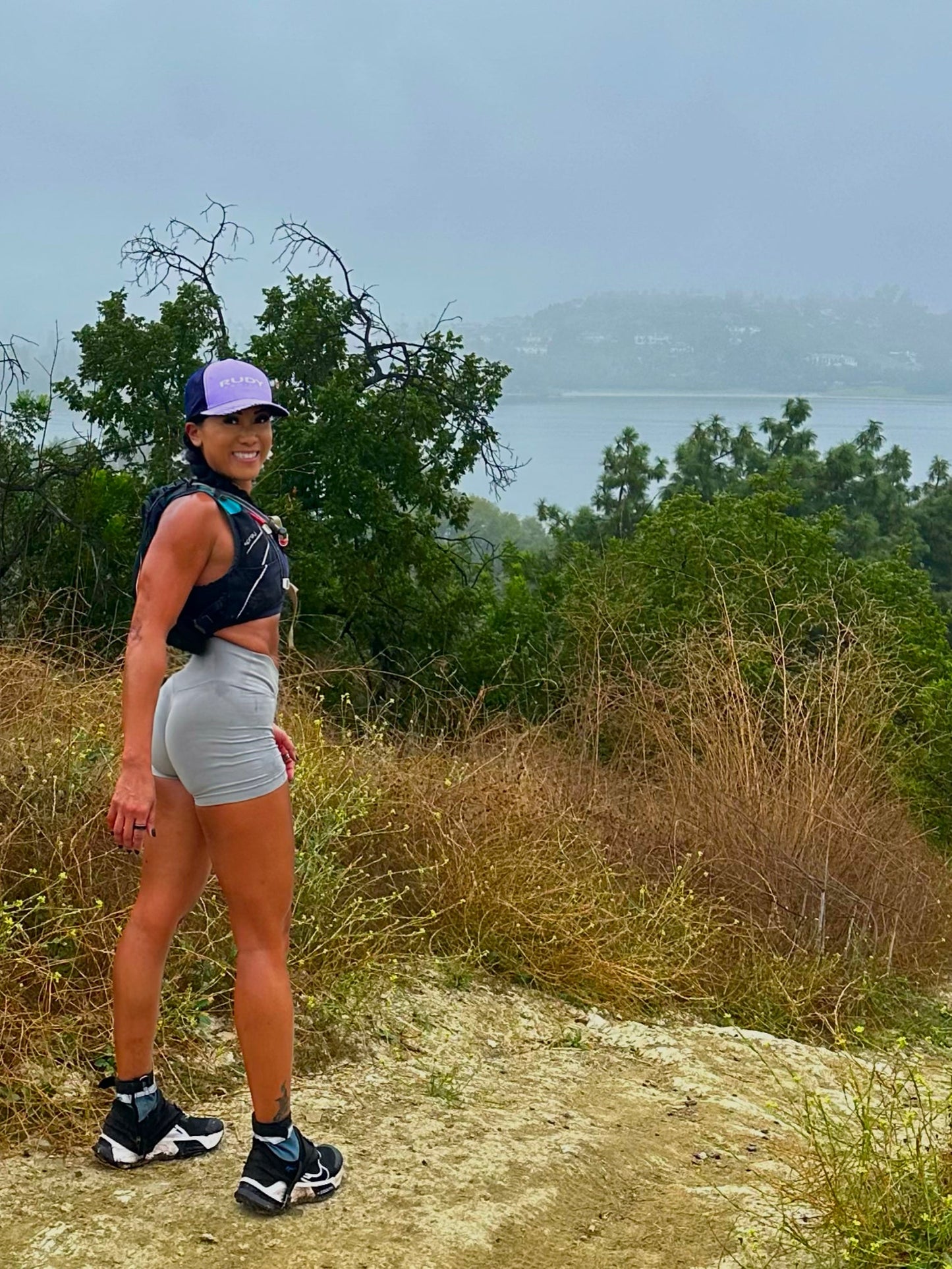 Hiker wearing black running gaiters with light blue panels on a trail