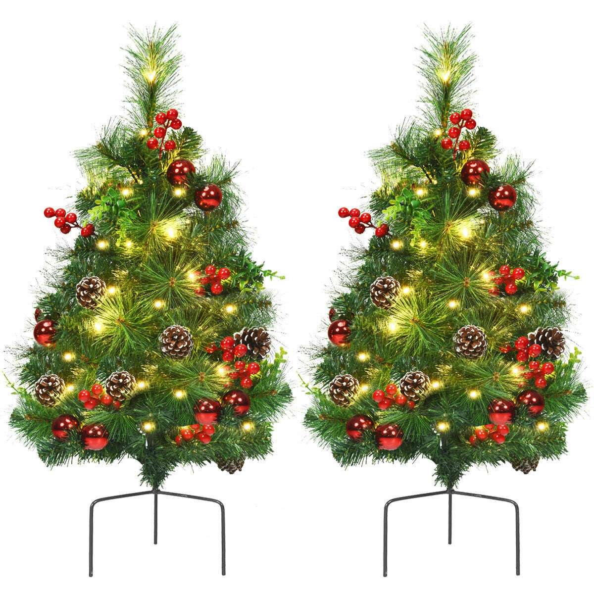 Pair of illuminated Christmas trees decorated with red berries, red ornaments, and pine cones