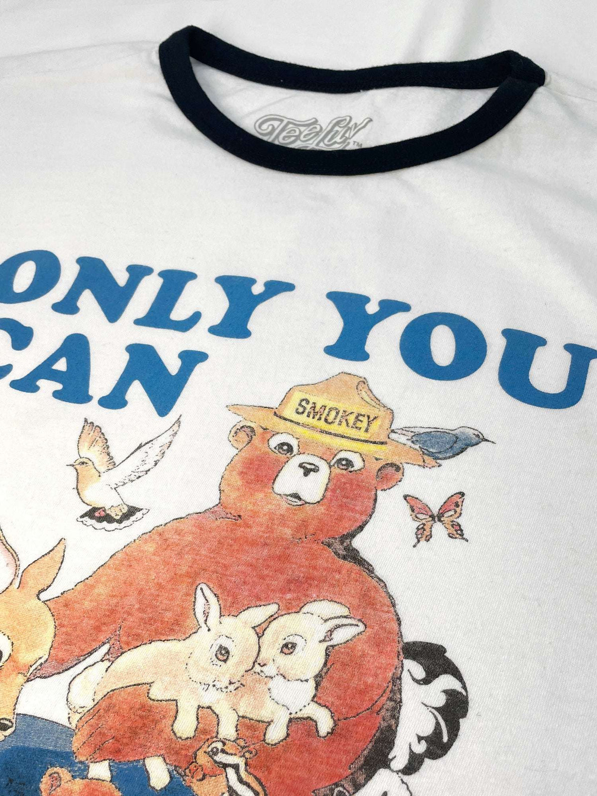 White ringer T-shirt close-up with black neck trim and Smokey character artwork