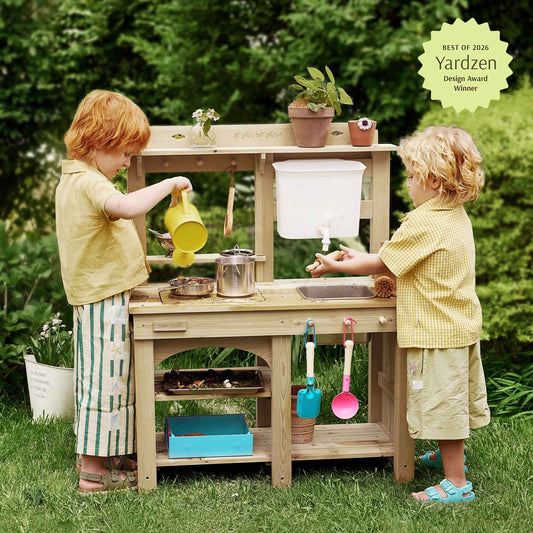 Children using wooden outdoor mud kitchen with faucet, pots, and colorful accessories