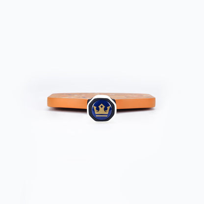 Orange pickleball paddle edge with blue circular logo medallion