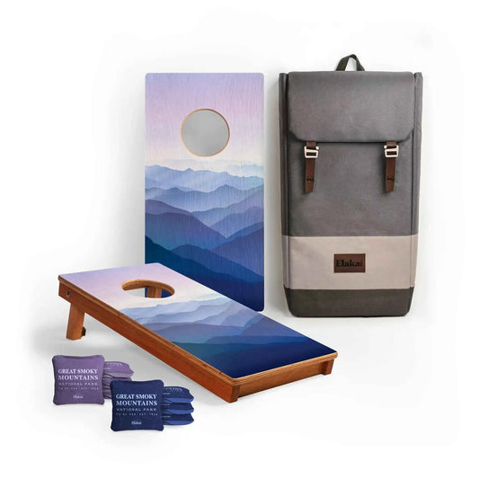 Two blue mountain cornhole boards with four purple bean bags and a gray carrying bag