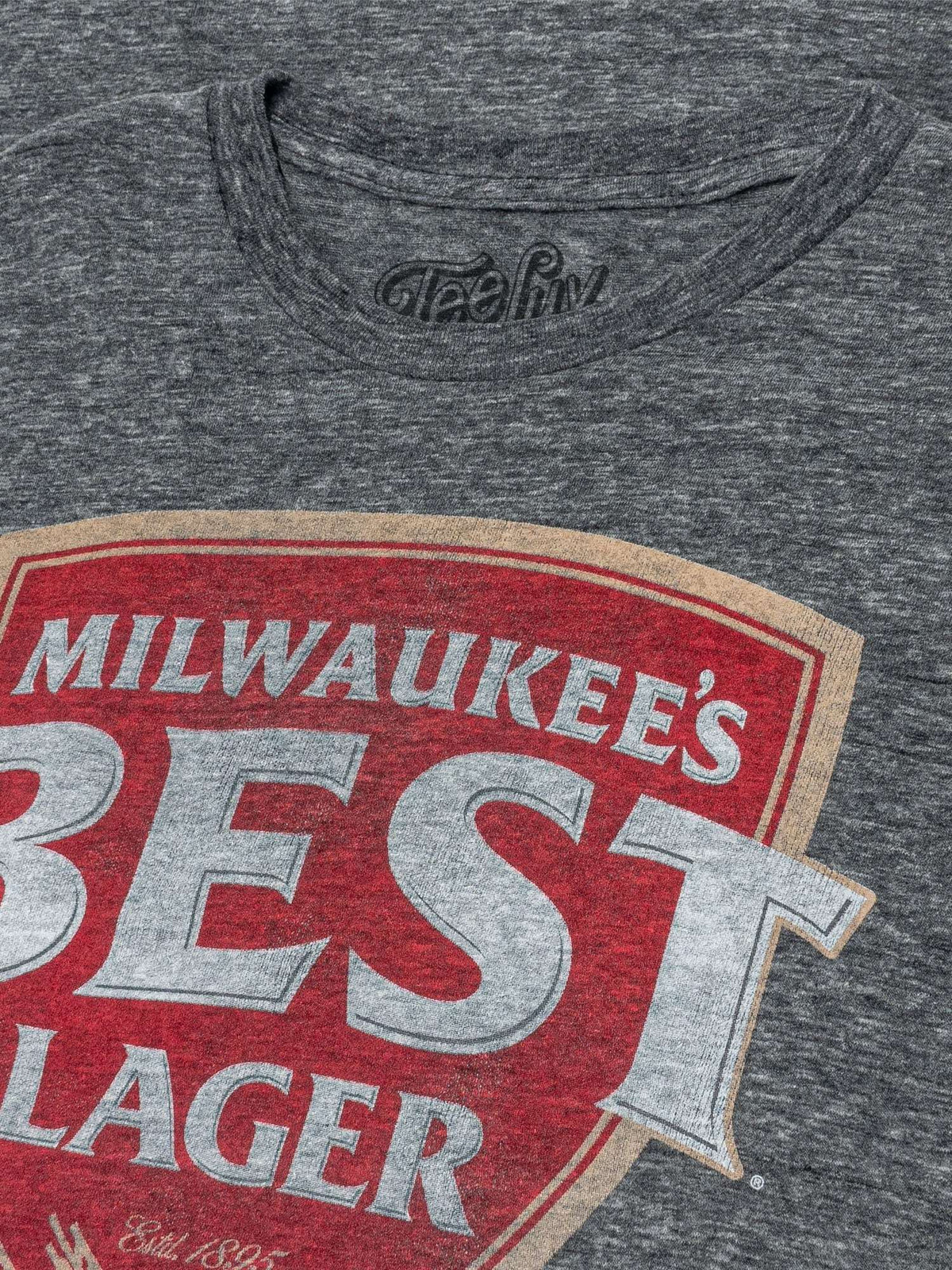 Gray T-shirt neckline with Milwaukee’s Best Lager logo partial front