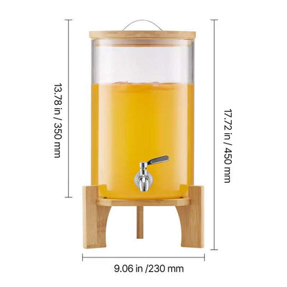 Clear glass beverage dispenser filled with orange drink, bamboo stand and metal spigot