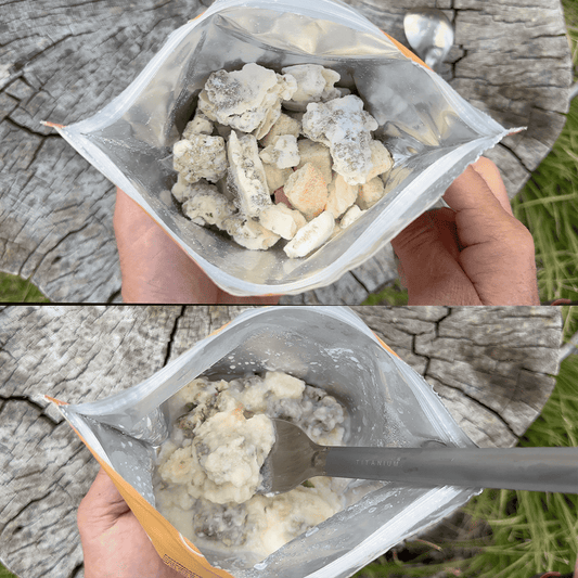 Clear pouch of freeze-dried biscuits and gravy pieces held in hand outdoors