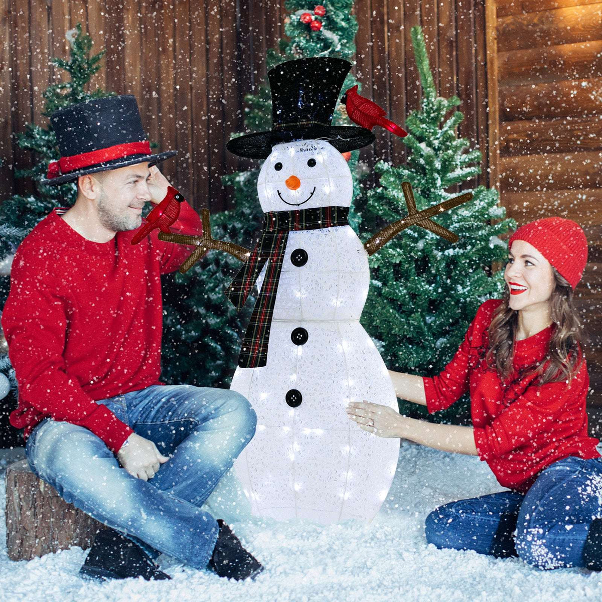 Lighted snowman decoration with plaid scarf, black hat and two redbirds, shown with people for scale