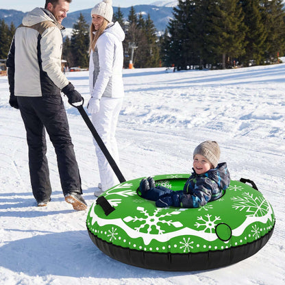 Green inflatable snow tube with snowflake design and tow strap, child riding in snow