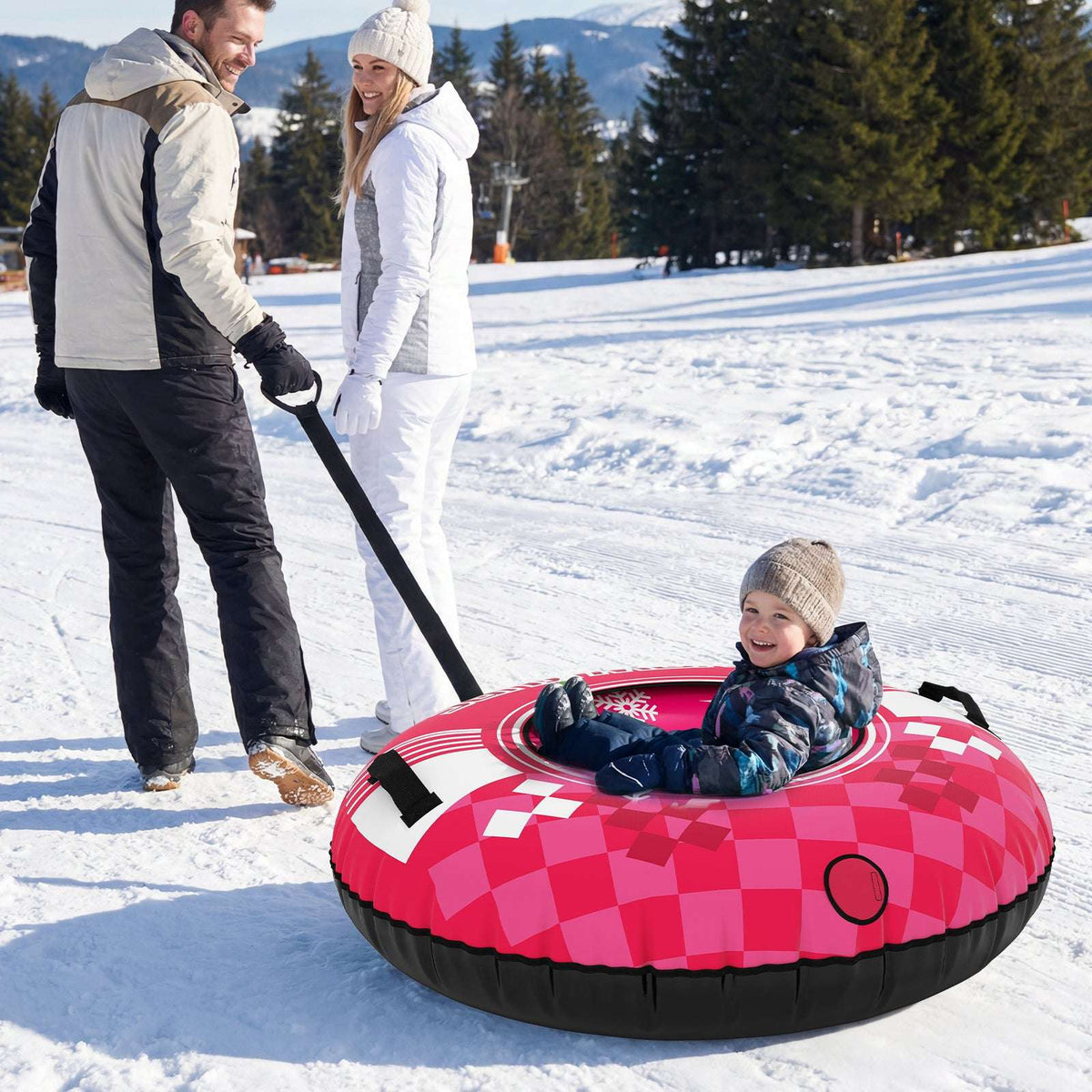 Red inflatable snow tube with snowflake design and tow strap, child riding in snow