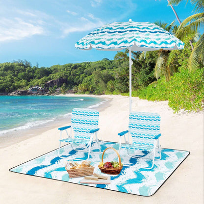 Blue umbrella with two striped chairs and picnic blanket on the beach