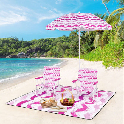 Pink umbrella with two striped chairs and picnic blanket on the beach