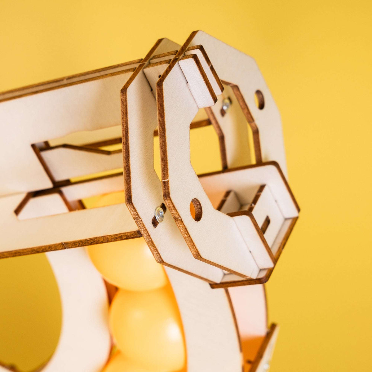 Wooden ball launcher mechanism close-up with ball guide and moving frame