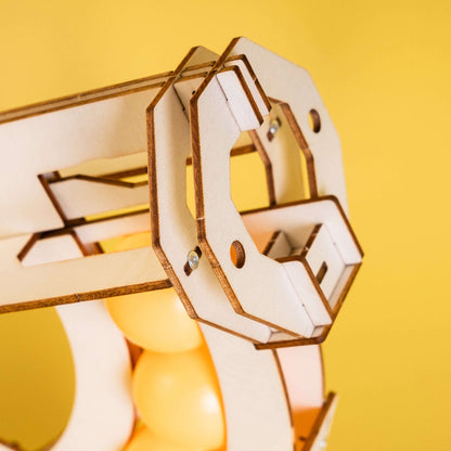 Wooden ball launcher mechanism close-up with ball guide and moving frame
