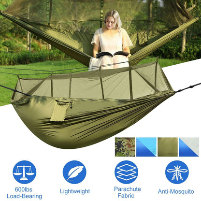 Olive green two-person hammock with mosquito net, person seated inside
