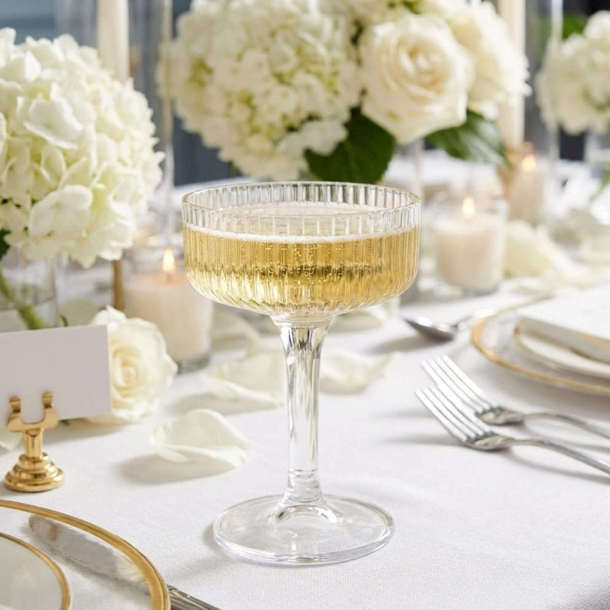 Single clear acrylic champagne coupe glass with gold drink on a decorated table
