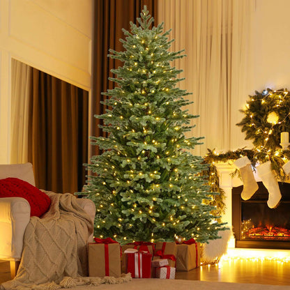 Tall artificial Christmas tree with warm white LED lights and a metal stand