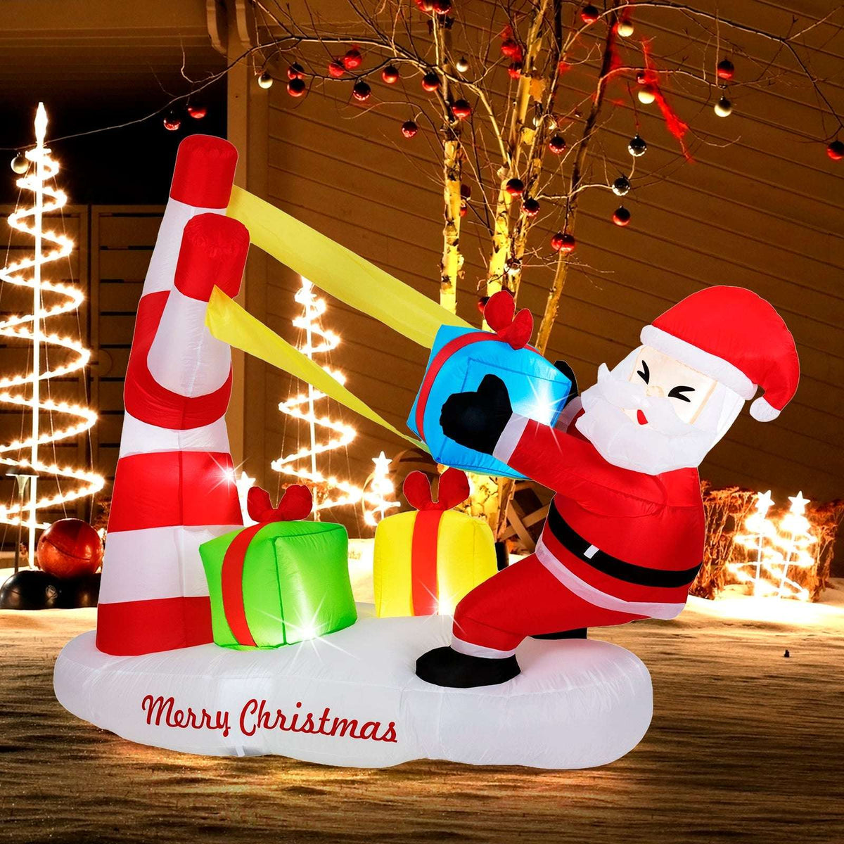 Inflatable Santa pulls a blue slingshot beside gift boxes on a white base