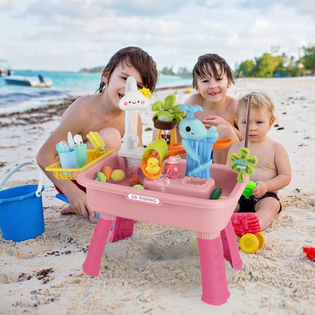 Children playing with 3-in-1 toy sink faucet and fishing game pieces on sand