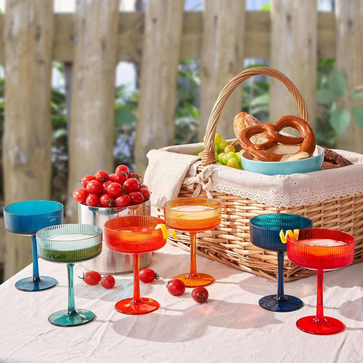 Outdoor picnic table display of 6 ribbed coupe acrylic glasses in assorted translucent colors