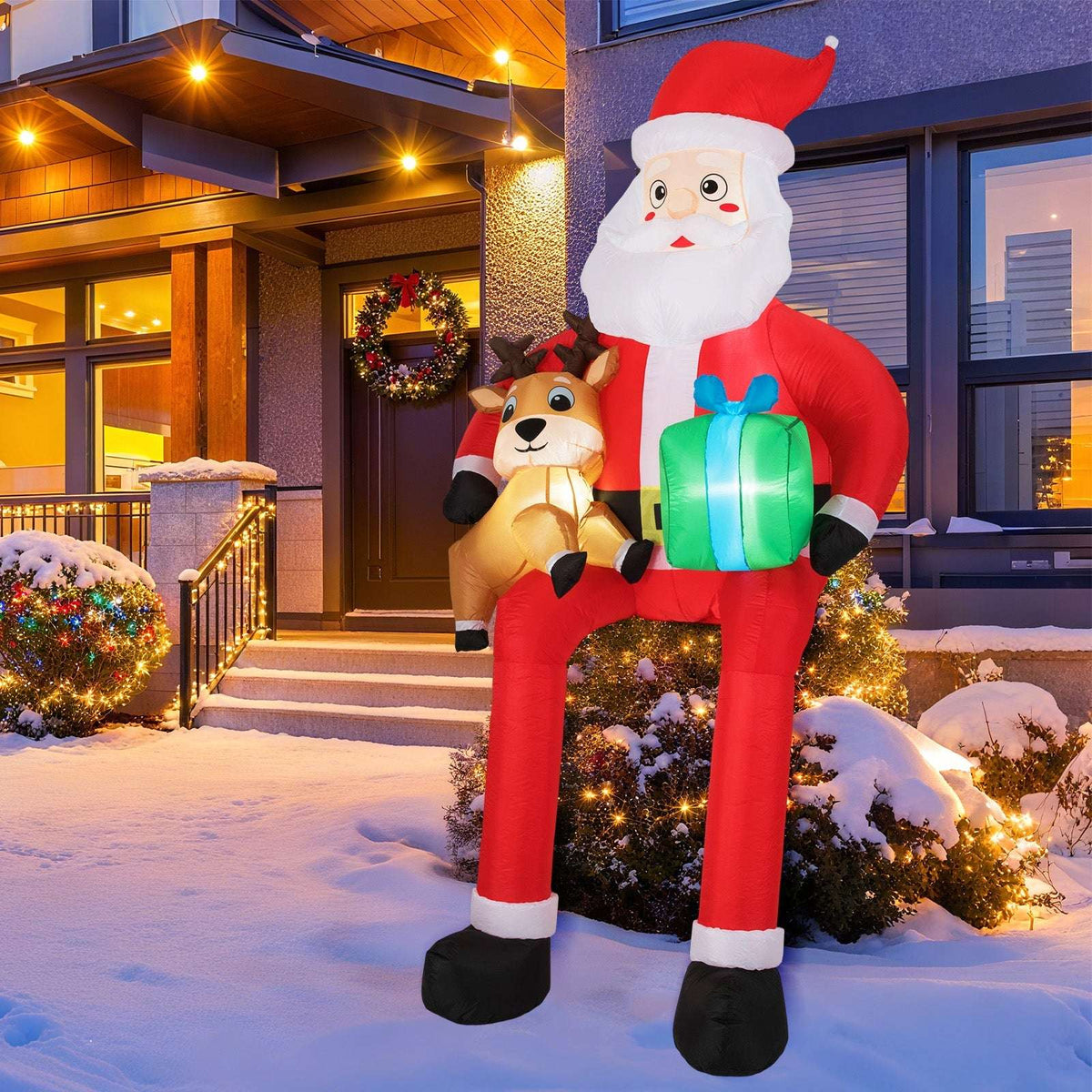 Inflatable Santa holding a reindeer and gift, displayed outdoors