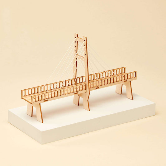 Wooden cable-stayed bridge model with two towers and cables on a display base