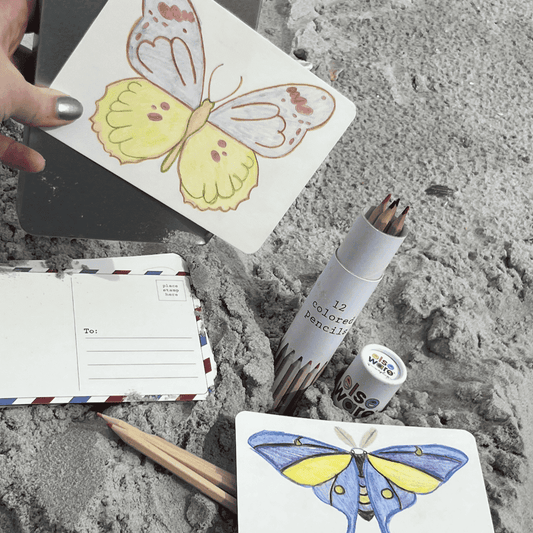 Hand holding a butterfly coloring postcard with colored pencils and blank cards