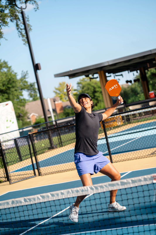 Orange patterned pickleball paddle held by a player on a court