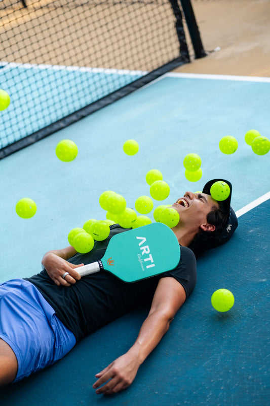 Mint pickleball paddle held during play, with tropical face and white grip.