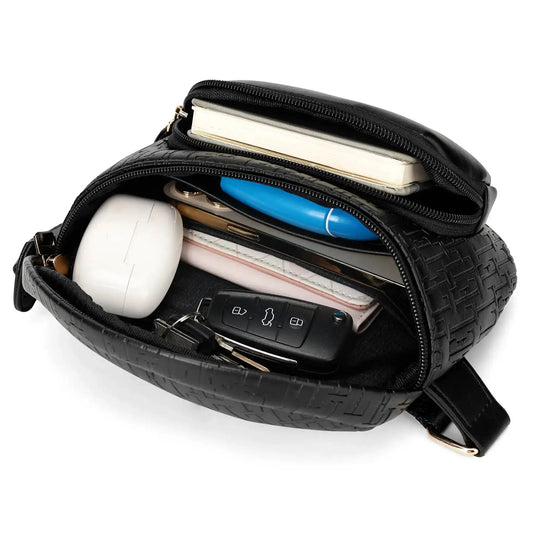 Black crossbody belt bag open to show interior pockets and items; adjustable strap