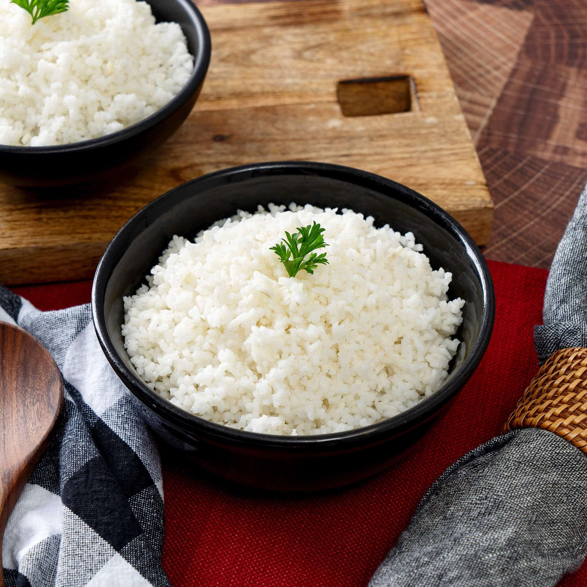 White rice in a black bowl garnished with a sprig