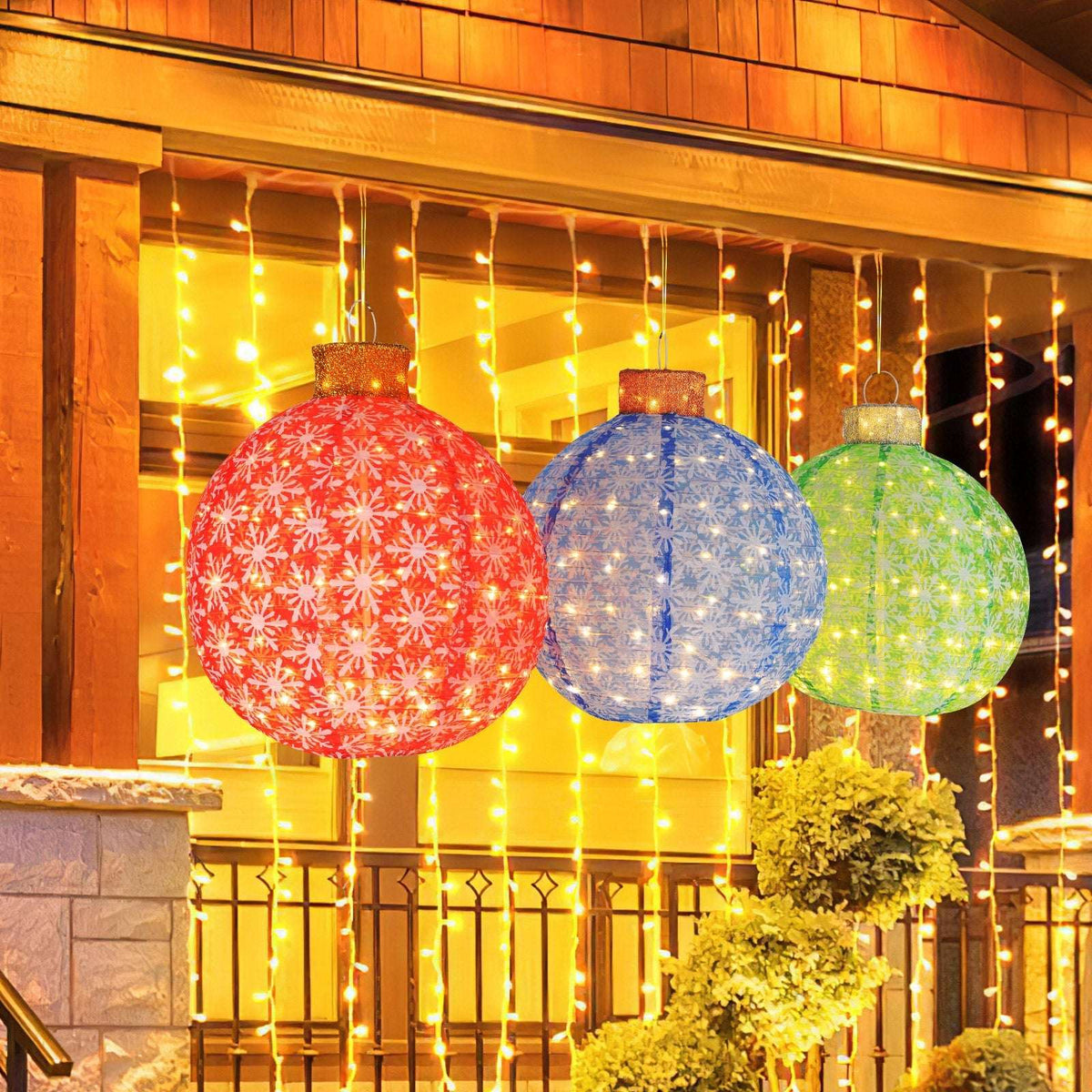 Three illuminated pop-up Christmas ball ornaments in red, blue, and green