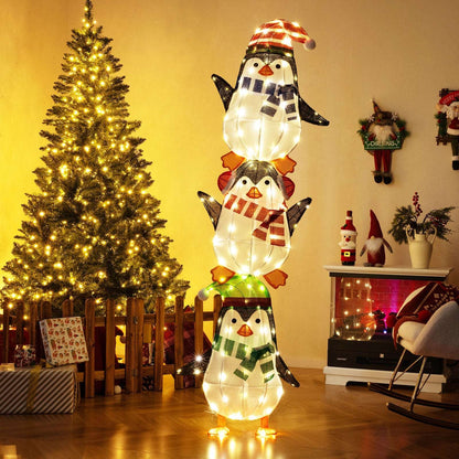 Stacked fabric penguins glowing with warm white lights, wearing festive hats and scarves.