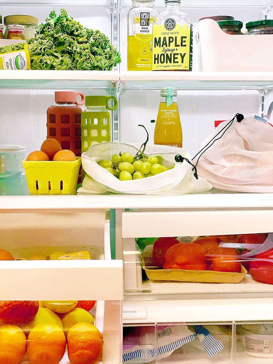 Reusable mesh produce bags set in fridge, white drawstring bags filled with fruit