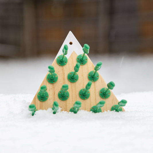 Triangular wooden peg game board with green pegs and mountain cutout