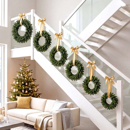 Six green artificial Christmas wreaths with gold ribbon bows displayed along a staircase