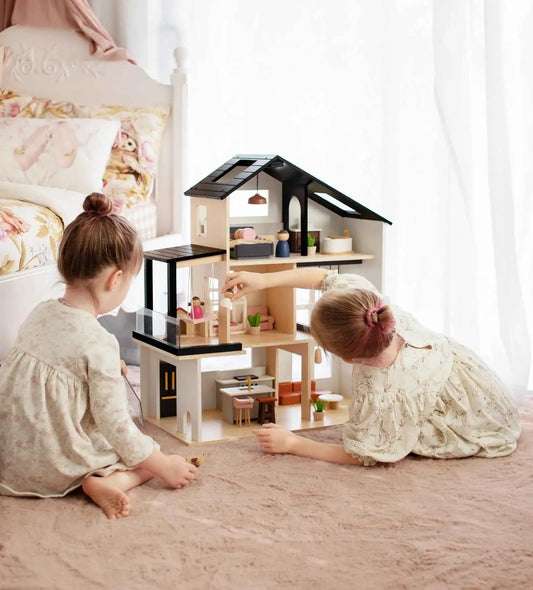 Children playing with a two-story dollhouse, dark roof, and open front rooms