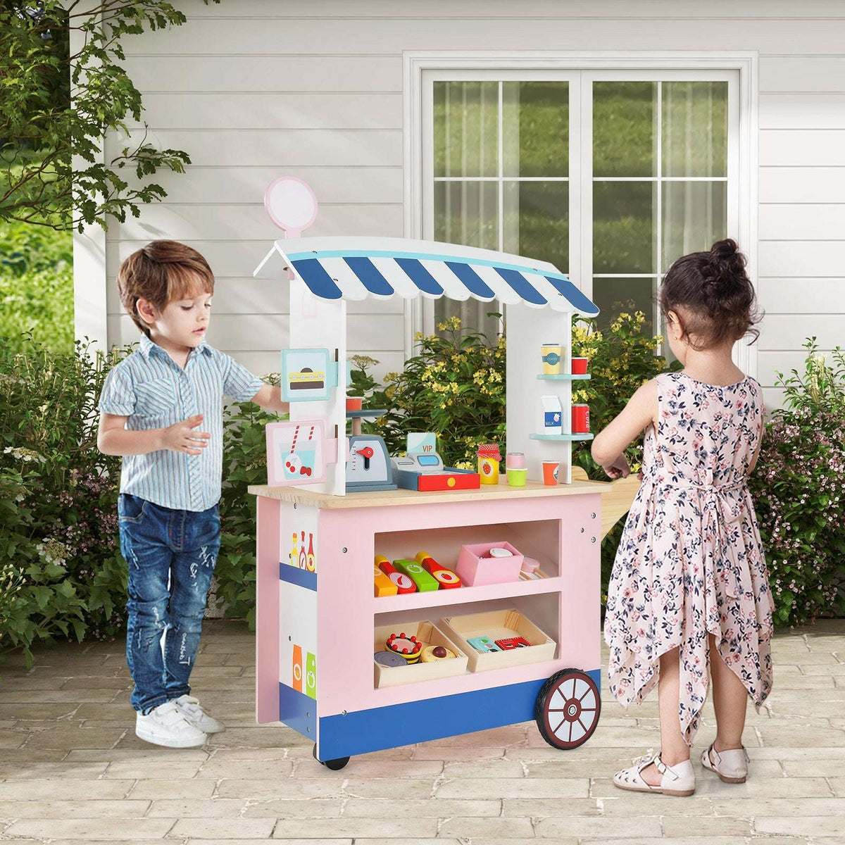 Pink toy market cart with blue and white canopy, shelves and checkout accessories beside two children
