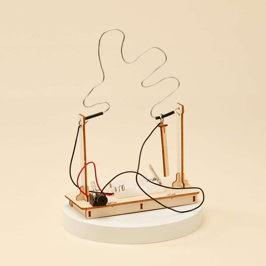 Buzz wire game kit assembled on wooden base with two posts and dangling wire loops